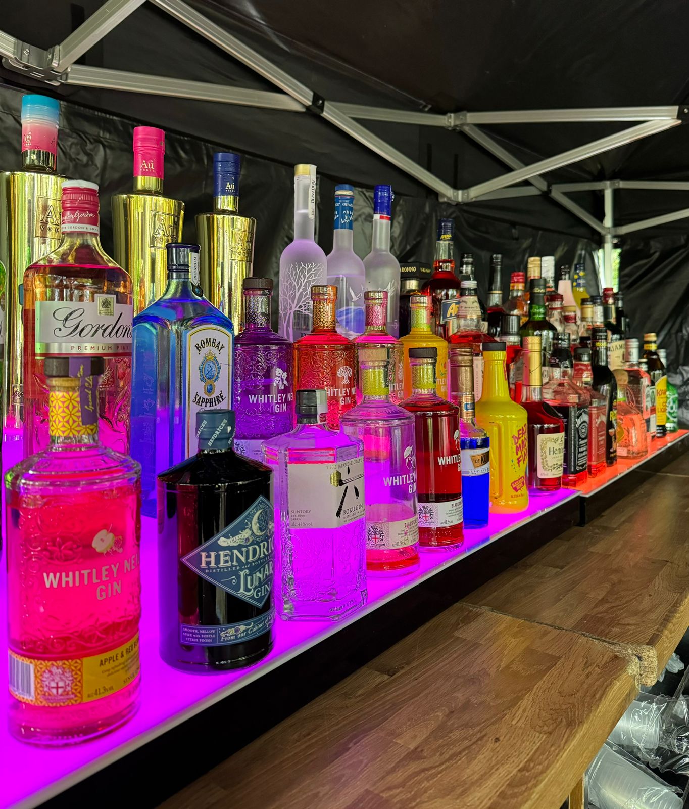 Premium spirits display with neon purple backlighting at an event bar