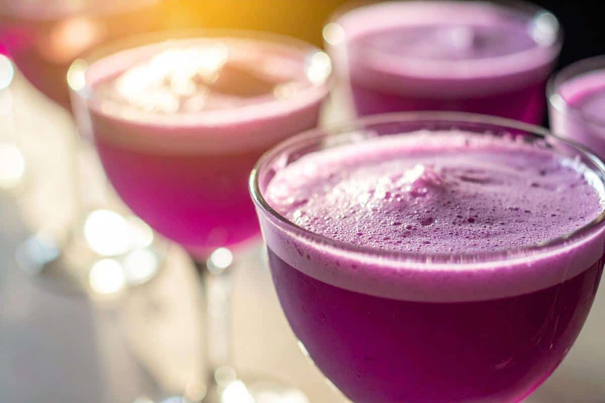 Purple cocktail glasses filled with colourful drinks, outdoor event, mobile bar hire London Berkshire, vibrant bar setup, event catering, The Sesh Bars.