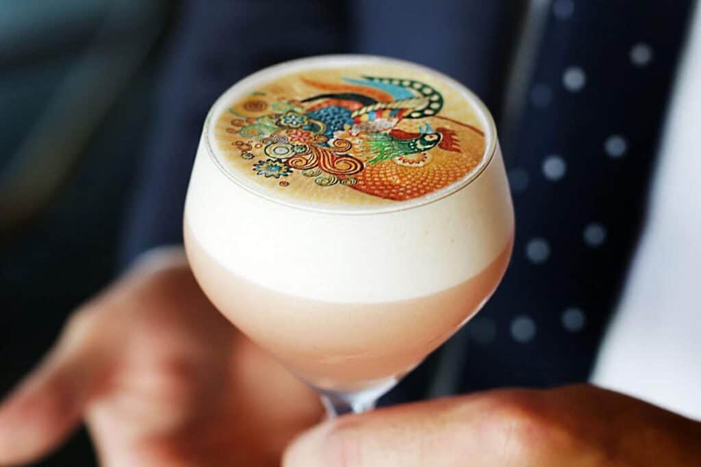 Bright cocktail in a glass with a colourful, intricate dragon design on the foam, perfect for events.