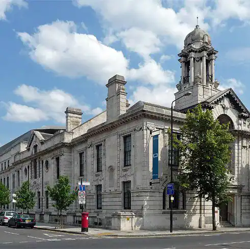 London historic building with classic architecture and clock tower, set against a bright blue sky with clouds.