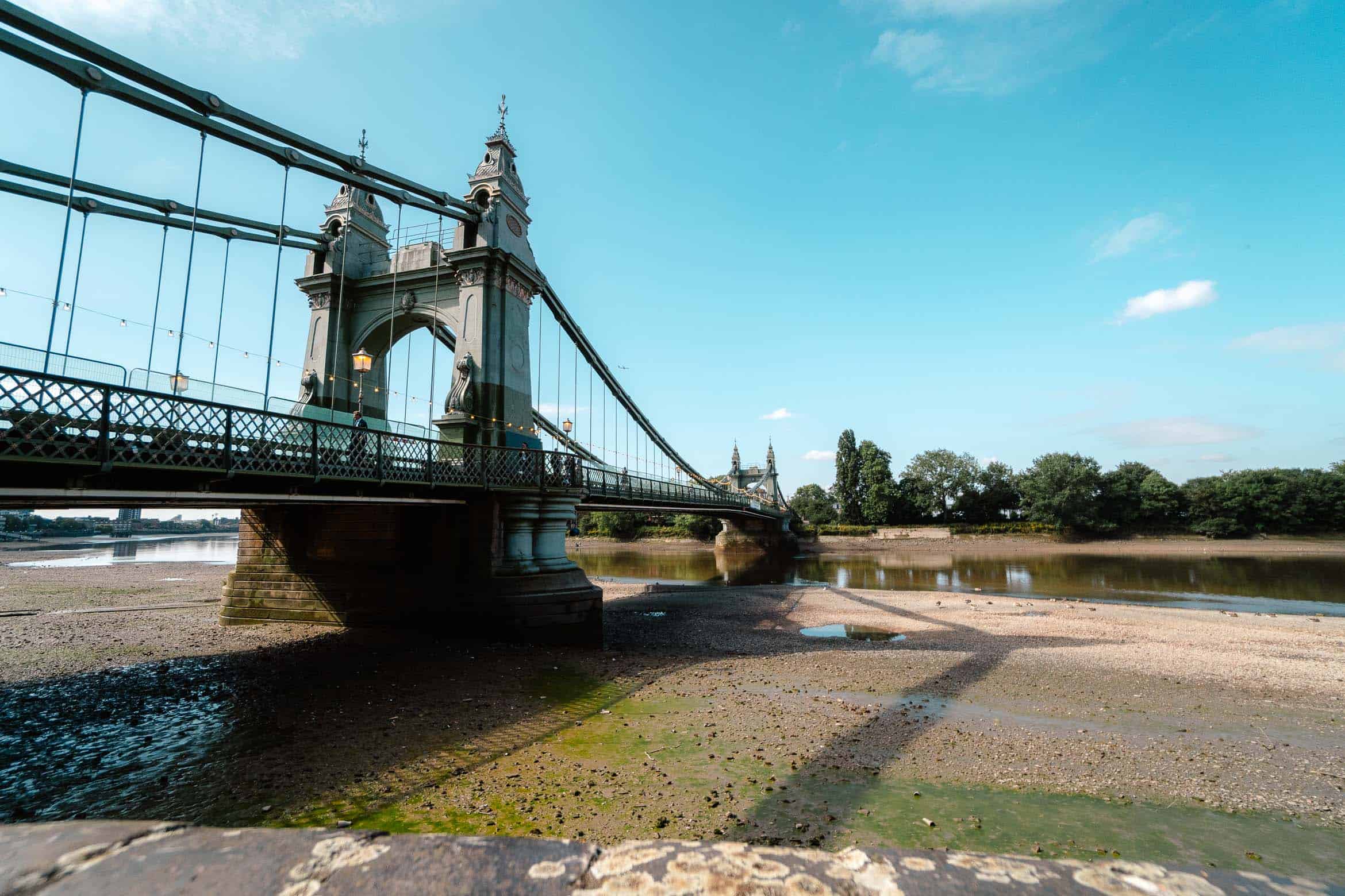 Bridge over the River Thames in London, showcasing the iconic suspension structure and scenic surroundings on a clear day.