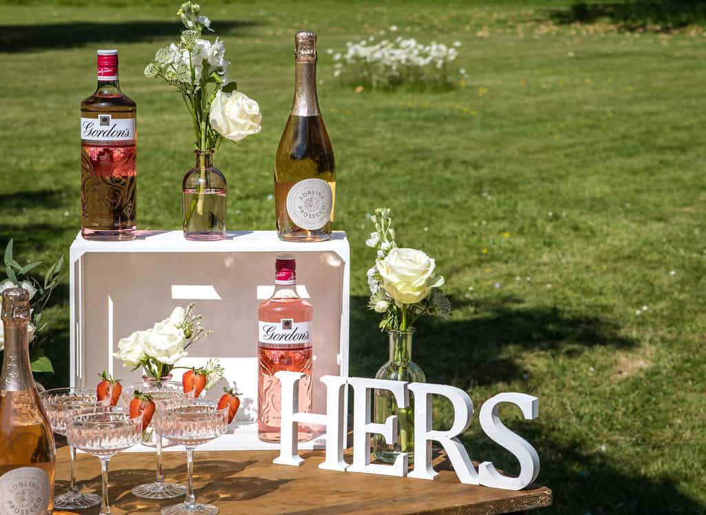 Glamorous outdoor bar setup with floral decorations and bottles of rosé wine, ideal for stylish events by The Sesh Bars Mobile Bar Hire London & Berkshire.