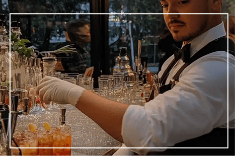 Mobile bar bartender preparing colourful cocktails at an outdoor event in London, offering premium bar hire services for parties and special occasions.