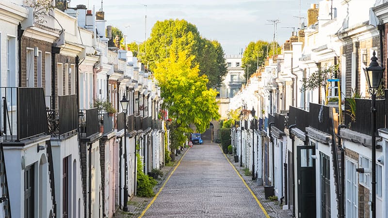 Vintage terraced houses lining a narrow street with cobbled pavement and greenery, showcasing classic London architecture. Perfect setting for outdoor events with The Sesh Bars mobile bar hire services in London & Berkshire.